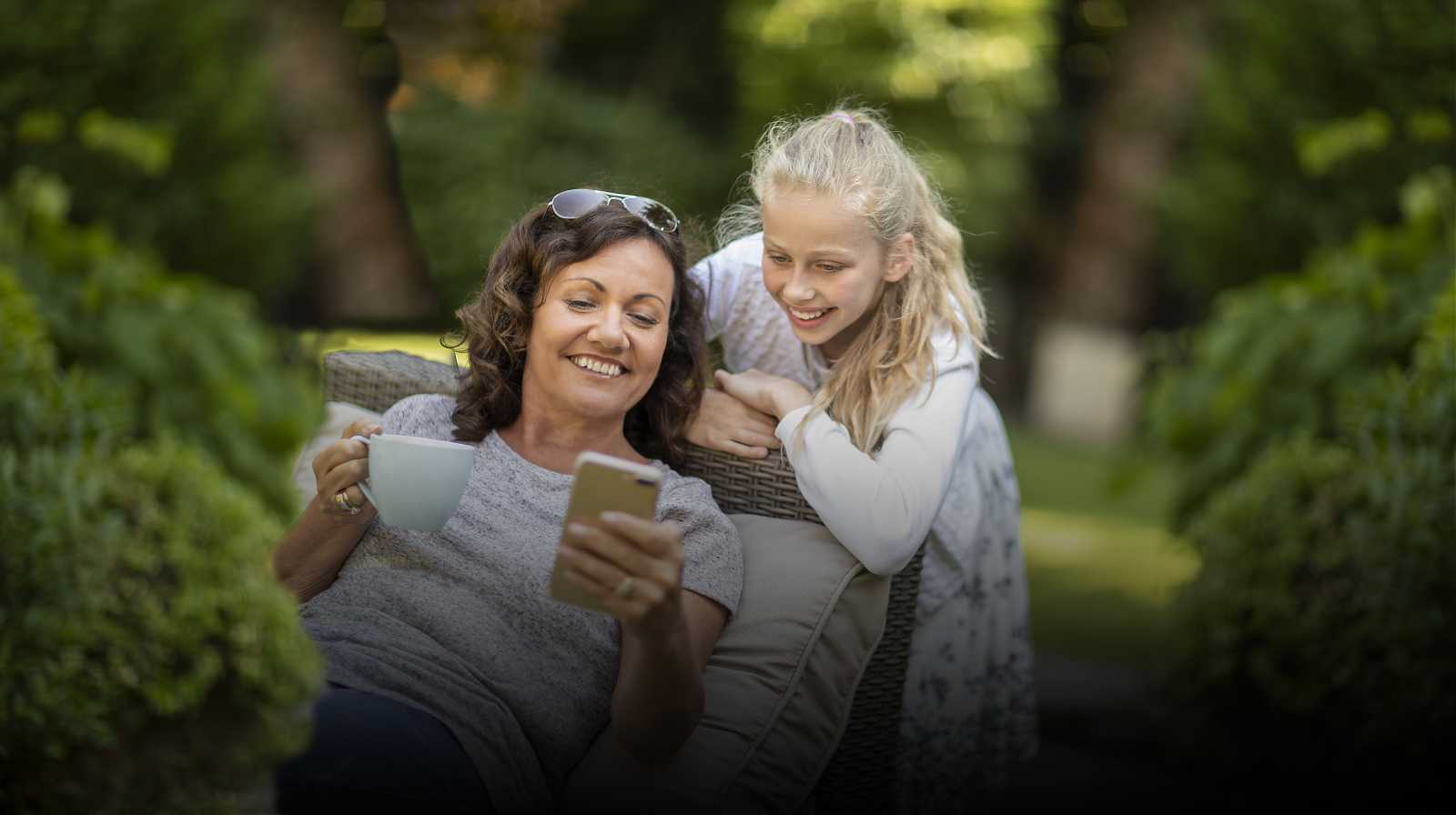 madre e hija mirando la pantalla de un teléfono móvil
